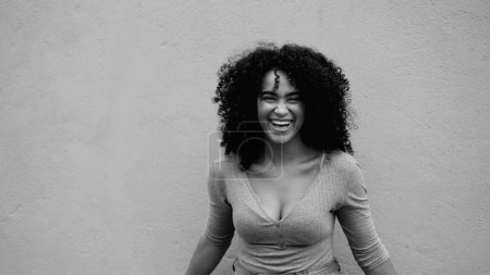 Foto de Mujer joven afroamericana carismática riendo y sonriendo en blanco y negro. Feliz alegre 20s persona de ascendencia africana en monocromo - Imagen libre de derechos