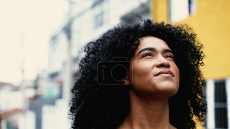Believing African American Woman Feeling Presence of Higher Power, Inspired Skyward Close-Up Face looking up in urban setting. One contemplative young black woman having HOPE