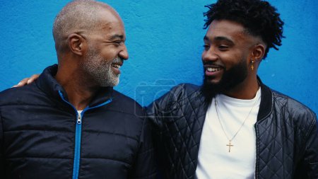 Photo for Happy African American Father and Son genuine bonding moment, middle-aged 50s dad with his adult 20s son exhanging affectionate moment standing in urban environment outside - Royalty Free Image