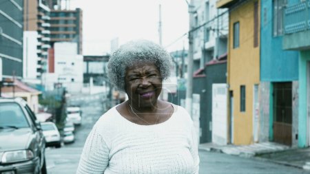 Photo for South American Senior black lady standing in city outside smiling at camera. 80s older person with gray hair in Brazilian environment - Royalty Free Image