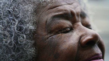 Foto de Agradecido Senior mujer afroamericana macro primeros ojos y cara mirando hacia arriba en el cielo con FE y ESPERANZA. cerrar y abrir los ojos en la ORACIÓN meditativa - Imagen libre de derechos