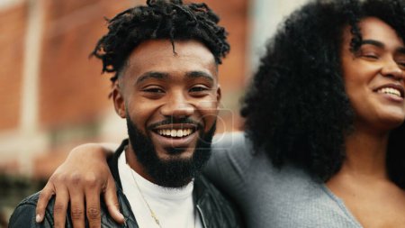 Photo for Young Happy African American couple smiling and laughing together, woman with arm around boyfriends in candid laughter outside in urban setting - Royalty Free Image