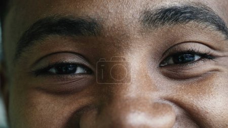 Foto de Macro primer plano ojos de un joven feliz hombre negro sonriendo a la cámara, rasgos faciales detalle de la persona con amplia sonrisa, persona de ascendencia africana sentirse positivo - Imagen libre de derechos