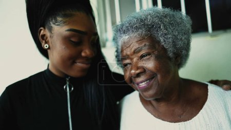 La petite-fille attentionnée embrasse la grand-mère âgée des années 80 sur le front en signe d'amour profond et de soutien du moment familial intergénérationnel. Personnes afro-américaines
