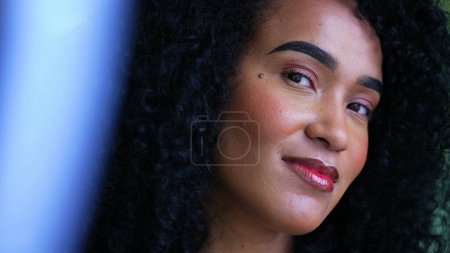 Foto de Una joven mujer brasileña retrato mirando a la cámara sonriente, apretado primer plano cara de una persona alegre con el pelo rizado de ascendencia africana en los años 20 - Imagen libre de derechos