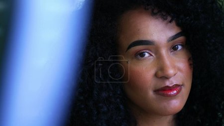 Foto de Una joven mujer brasileña retrato mirando a la cámara sonriente, apretado primer plano cara de una persona alegre con el pelo rizado de ascendencia africana en los años 20 - Imagen libre de derechos