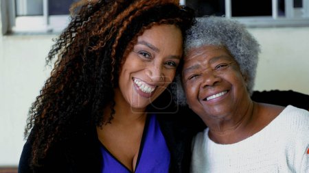Foto de Feliz retrato de la hija afroamericana adulta con el brazo alrededor de la madre anciana de los años 80. Rostros cercanos de mujeres alegres intergeneracionales con el brazo alrededor del hombro - Imagen libre de derechos