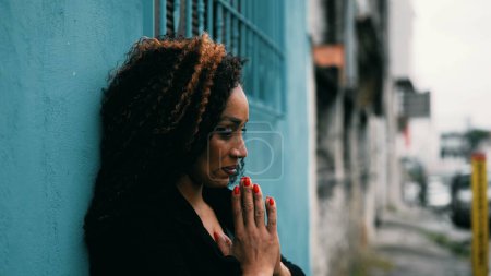 Photo for Preoccupied hispanic middle-aged latin woman of African descent in Prayer in urban environmen outside seeking hope and help during challenging times in deep mental contemplation - Royalty Free Image