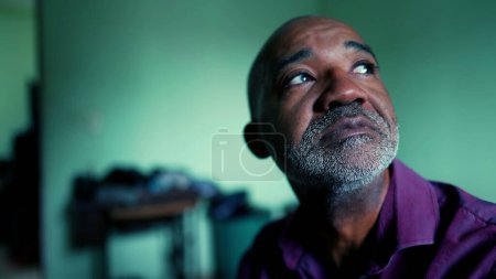 Photo for One hopeful senior black man seeking faith during challenging times, close-up face of 50s person of African descent gazing at window in moody bedroom aspiring for optimism - Royalty Free Image