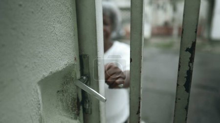 Téléchargez les photos : Une dame noire âgée ouvre la porte d'entrée de la résidence depuis le trottoir urbain et monte les escaliers pour rentrer chez elle. Humble Senior cheveux gris Afro-Américaine arrive à la résidence - en image libre de droit