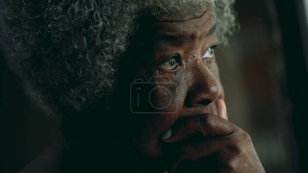 Photo for Contemplative African American elderly woman gazing out in the distance in deep mental reflection. One black lady thoughtful expression pondering solution - Royalty Free Image
