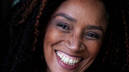 Foto de Una mujer negra de mediana edad feliz de cerca sonriendo a la cámara. Mujer sudamericana de ascendencia africana - Imagen libre de derechos
