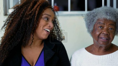Téléchargez les photos : Afro-américaine adulte fille authentique interaction avec les personnes âgées 80 mère échanger des regards tout en riant et souriant, authentiques visages authentiques heureux d'âges contrastés - en image libre de droit