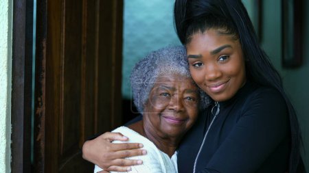 Photo for African American Grandmother and Granddaughter Showing Age Contrast, young woman with arm around elderly 80s lady in caring and tender moment between intergenerational bond - Royalty Free Image