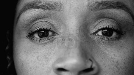 African American 50s woman macro close-up eyes looking at camera in black and white. Monochromatic facial feature detail