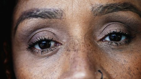 Photo for One black hispanic middle-aged 50s woman macro close-up eyes looking at camera with solemn serious gaze, South American person of African descent - Royalty Free Image