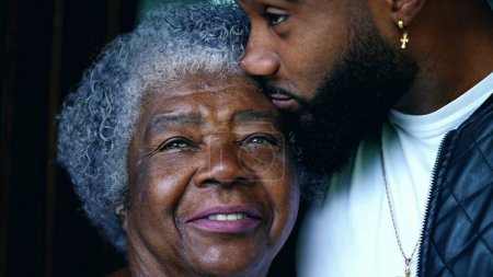 Téléchargez les photos : Jeune petit-fils afro-américain avec grand-mère âgée, Gros plan sur deux générations de visages contrastés âges. Étreinte familiale - en image libre de droit