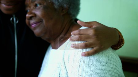 Zärtliche Umarmung der afroamerikanischen Großmutter durch die Teenage Enkelin, ein generationenübergreifendes Familienmitglied, das sich in den 80er Jahren um eine ältere runzlige Frau mit grauen Haaren kümmert