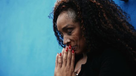Photo for One worried hispanic black woman seeking solace during hard times Praying to GOD in urban setting gazing upwards with HOPE and FAITH - Royalty Free Image