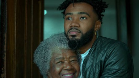 Téléchargez les photos : Afro-américain jeune petit-fils posant pour caméra avec grand-mère cheveux gris âgés, deux générations différentes gros plan visages - en image libre de droit