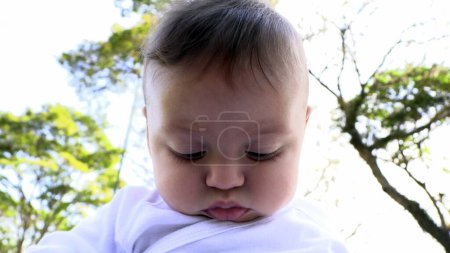 Téléchargez les photos : Portrait de bébé garçon au parc nature regardant en bas - en image libre de droit