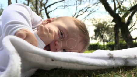 Foto de Hermoso adorable bebé lindo niño acostado en la hierba en la exploración al aire libre descubrir mundo - Imagen libre de derechos