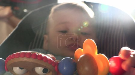Téléchargez les photos : Mignon tout-petit dans la chaise de bébé jouer avec jouet découvrir le monde - en image libre de droit