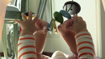 Foto de Lindo bebé sosteniendo los pies con la mano y jugando con juguetes de madera - Imagen libre de derechos