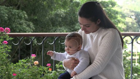Téléchargez les photos : Candid mère tenant bébé au balcon maison - en image libre de droit