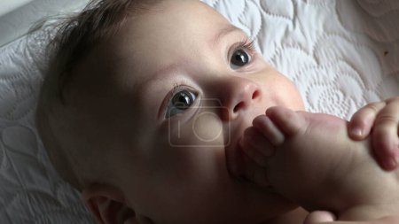 Téléchargez les photos : Bébé mignon mettre les pieds et les orteils dans la bouche - en image libre de droit