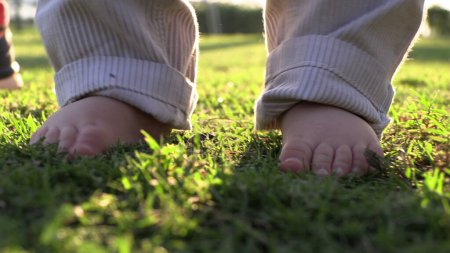 Téléchargez les photos : Bébé pieds droits apprendre à marcher dans l'herbe de la nature - en image libre de droit