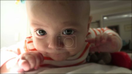 Photo for Cute baby infant closeup face learning to crawl lying on ground - Royalty Free Image