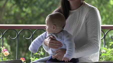 Téléchargez les photos : Mère tenant bébé enfant en bas âge fils par fenêtre - en image libre de droit