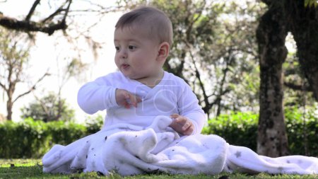Téléchargez les photos : Joyeux petit enfant bébé garçon se sentant la joie assis au parc extérieur - en image libre de droit