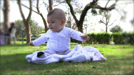 Téléchargez les photos : Bébé bébé mignon au parc à l'extérieur assis dans l'apprentissage de l'herbe - en image libre de droit