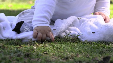 Téléchargez les photos : Joyeux bébé assis à l'herbe du parc à l'extérieur sentiment de joie - en image libre de droit