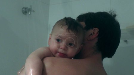 Foto de Padre bañarse y lavar bebé niño pequeño hijo en la ducha - Imagen libre de derechos