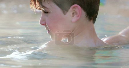 Photo for Child throwing something inside heated swimming pool water - Royalty Free Image