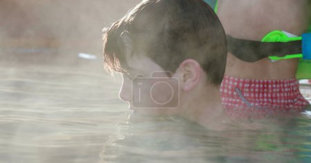 Photo for Child inside warm swimming pool water, heated water evaporating - Royalty Free Image