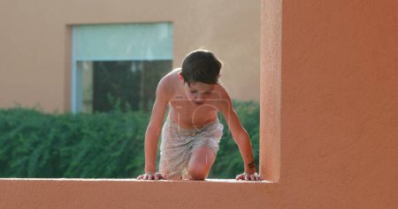 Photo for Child climbing on top of wall at the pool with effort - Royalty Free Image