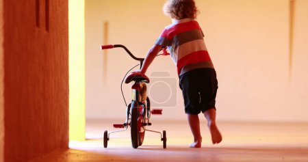 Photo for Small boy carrying trycicle, child learning to ride trycicle - Royalty Free Image