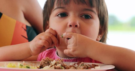 Photo for Cute little girl child eating meal with hands and fingers - Royalty Free Image