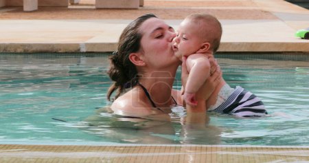 Foto de Feliz madre joven y amorosa en el agua de la piscina con el bebé recién nacido hijo - Imagen libre de derechos