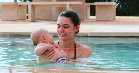 Téléchargez les photos : Mother and newborn baby son inside swimming pool water having fun - en image libre de droit