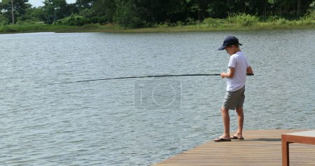 Foto de Little boy fishing at lake, child in outdoor activity - Imagen libre de derechos