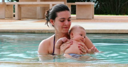 Téléchargez les photos : Mother and newborn baby son inside swimming pool water having fun - en image libre de droit