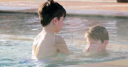 Photo for Siblings dispute. Small brothers fighting splashing water inside pool, real life, candid - Royalty Free Image