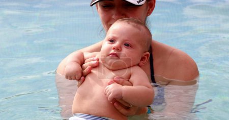 Foto de Mother and infant newborn baby at the swimming pool for the first time - Imagen libre de derechos