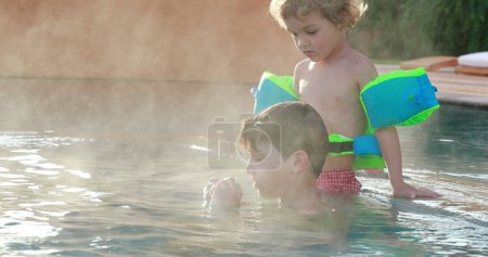 Téléchargez les photos : Enfants dans l'eau chaude de la piscine - en image libre de droit