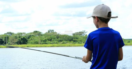 Foto de Young boy fishing at lake in outdoor activity - Imagen libre de derechos